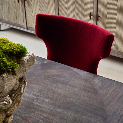 Dining room with magenta chair and black and white chair, and antique stone planters filled with moss